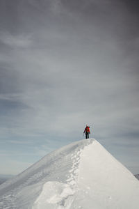 Low angle view of man standing on mountain against sky