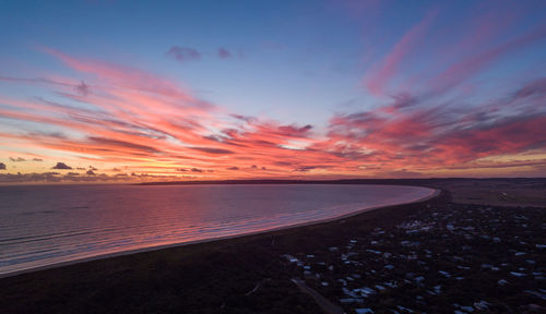 Road by sea against sky during sunset
