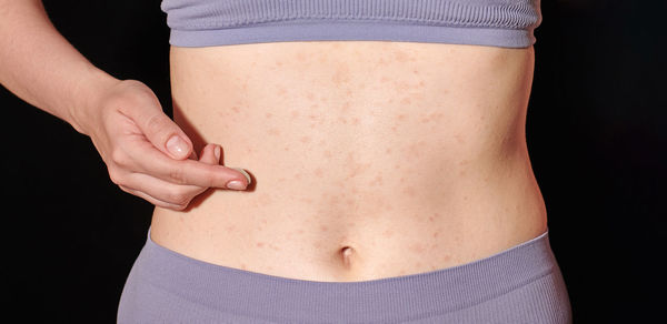 Midsection of woman standing against black background