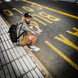 Young man with bicycle sitting on road