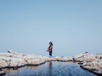 Full length of woman jumping on rock formation