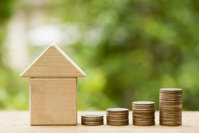 Close-up of coins and model home on wooden table