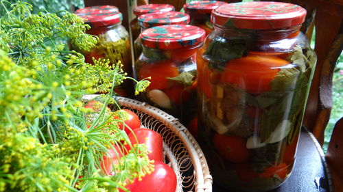 High angle view of tomatoes in bowl by jars and herbs on table