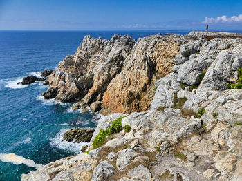 Scenic view of rocky shore by sea against sky