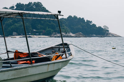 Fishing boat moored on sea against clear sky
