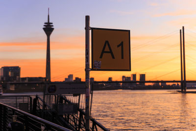 Information sign on bridge over river at sunset