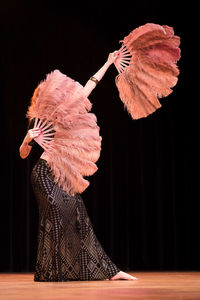 Midsection of woman dancing against black background