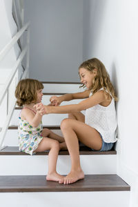 Side view of happy siblings playing on steps