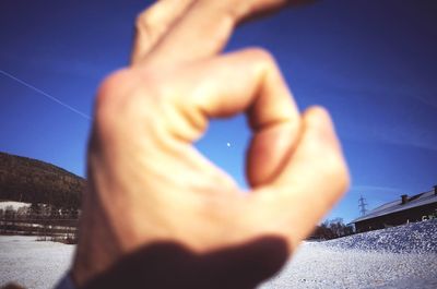 Close-up of hands against blue sky