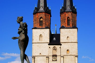 Low angle view of statue against blue sky and building