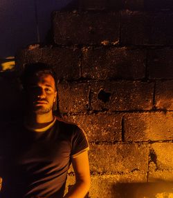 Portrait of young man standing against wall