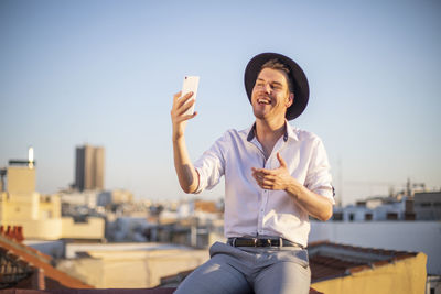 Handsome young singer performing for his fans on social media from the roof of his house during quarantine