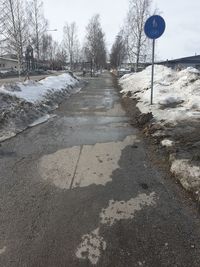 Snow covered road by trees in city