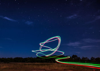 Light trails on field against sky at night