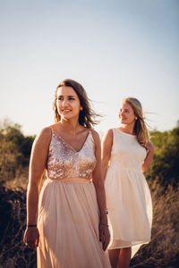 Young women standing against sky