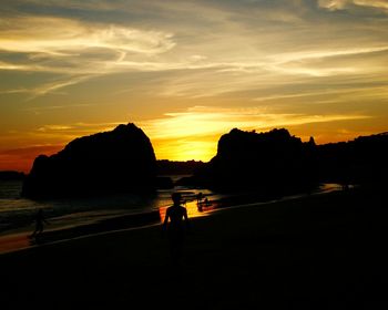 Silhouette man in sea against sky during sunset