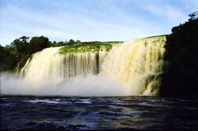 Scenic view of waterfall against sky