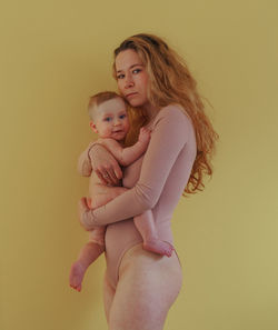 Portrait of mother and son against yellow background