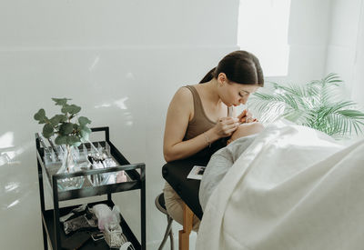 Portrait of a girl cosmetologist extending eyelashes to a woman.