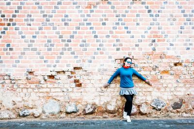 Full length of man standing against brick wall