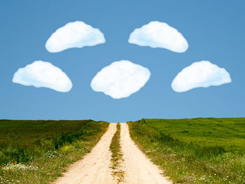 Panoramic shot of road amidst field against sky