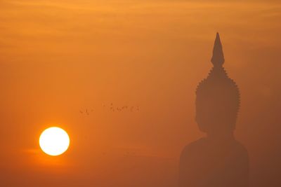 Close-up of silhouette buddha statue against sky during sunset