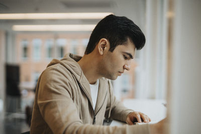 Side view of male student studying at table in university