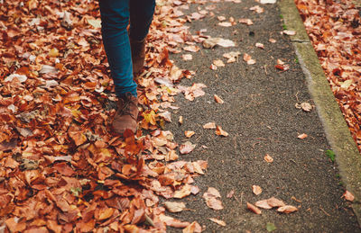 Low section of man walking on fallen leaves