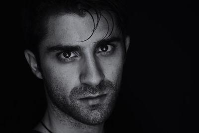 Close-up portrait of young man against black background