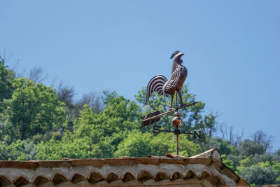 Low angle view of animal statue on roof top against clear sky