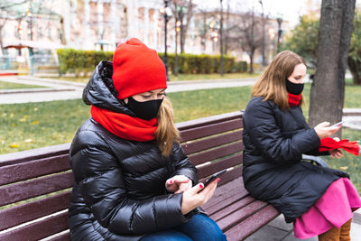 Woman sitting on mobile phone in winter