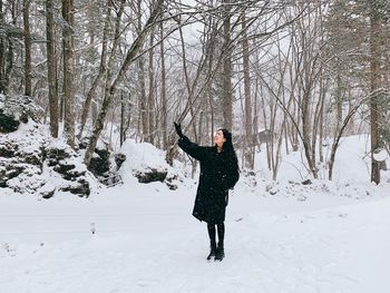 Full length of smiling mid adult woman standing on snow covered field