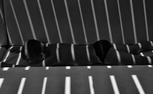 Side view of shirtless boy lying on sofa