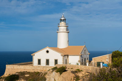 Lighthouse by sea against sky