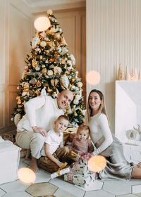 A family with children celebrate give gift boxes decorate a christmas tree in the interior the house