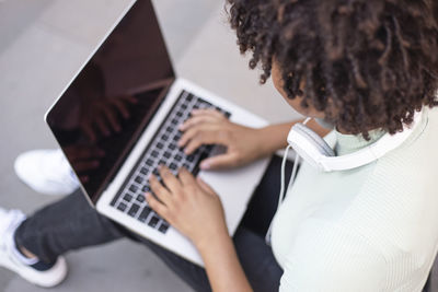 College student sitting on the stairs working on a laptop.