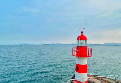 Lighthouse by sea against sky