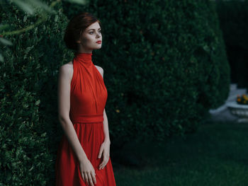 Woman looking away while standing against plants