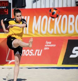 Girl scores a goal in beach soccer barefoot