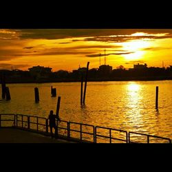 Silhouette of people in river at sunset