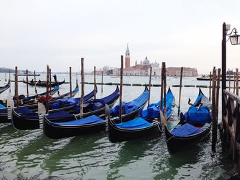 Gondolas moored in grand canal by san marco campanile against sky