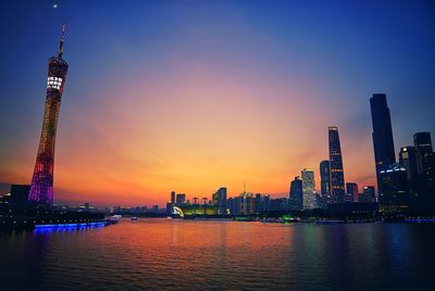 Canton tower by pearl river against sky at sunset