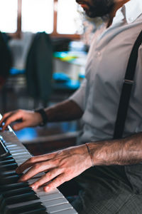 Midsection of man playing piano at home