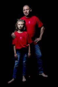 Portrait of mother and daughter against black background