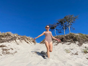Woman in a bathing suit runs down the embankment with joy on the beach