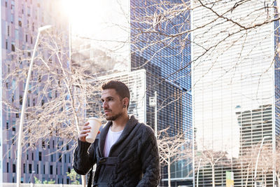 Bearded man walking in the street while holding a takeaway coffee