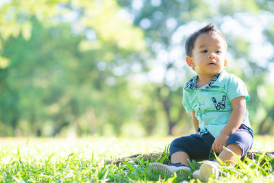 Cute boy sitting on grass at park