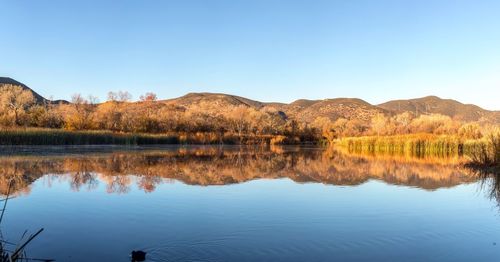 Scenic view of lake and mountains against clear blue sky