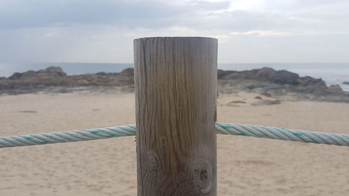 Close-up of wooden post at beach against sky