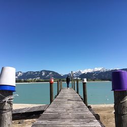 Pier over lake against clear blue sky